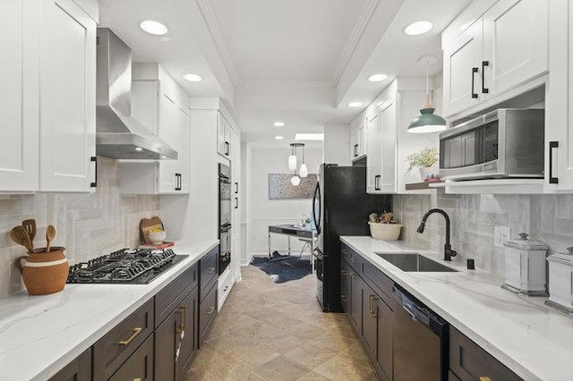 kitchen with pendant lighting, white cabinetry, ornamental molding, black appliances, and wall chimney exhaust hood