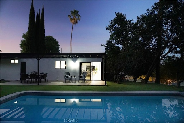 pool at dusk featuring a patio area and a yard