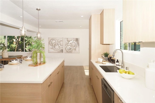 kitchen with light hardwood / wood-style floors, pendant lighting, light brown cabinetry, sink, and stainless steel dishwasher