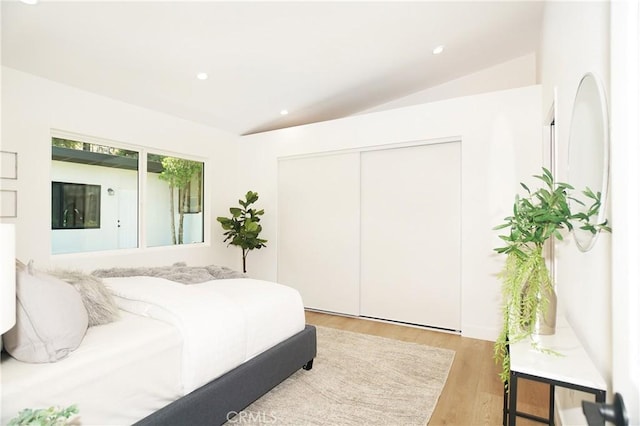 bedroom featuring light hardwood / wood-style floors, a closet, and lofted ceiling