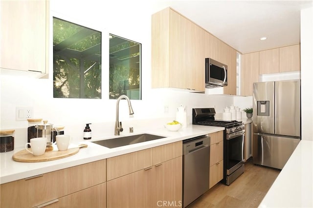 kitchen featuring appliances with stainless steel finishes, light hardwood / wood-style flooring, light brown cabinets, and sink