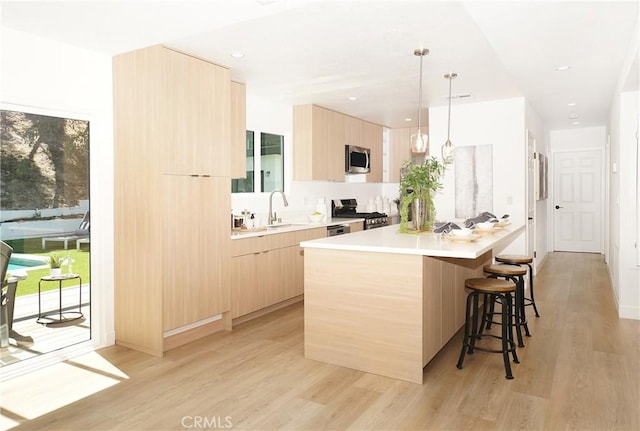 kitchen featuring pendant lighting, a center island, light hardwood / wood-style floors, appliances with stainless steel finishes, and light brown cabinets