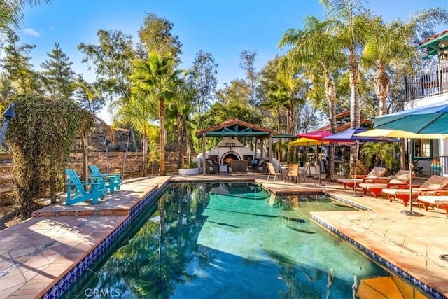 view of swimming pool with exterior fireplace, a patio area, and a gazebo