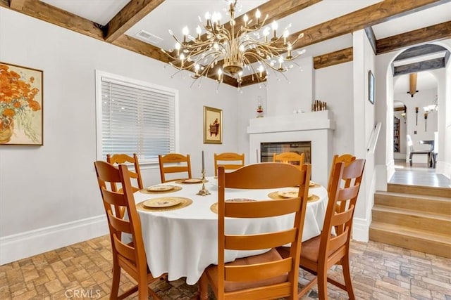 dining room featuring a notable chandelier and beamed ceiling