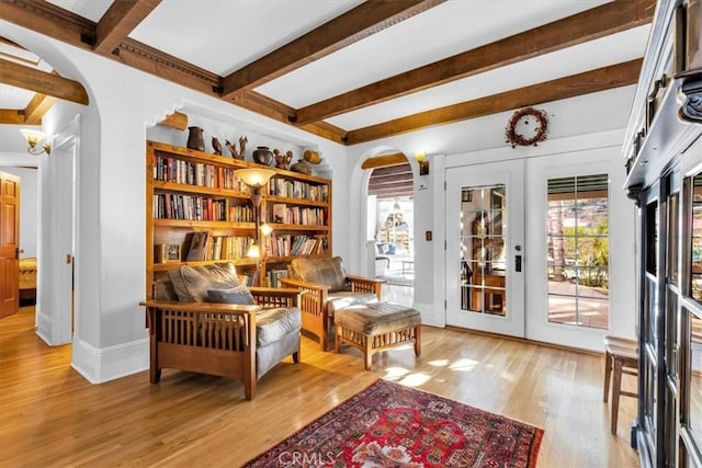 sitting room featuring light hardwood / wood-style floors, beam ceiling, and french doors