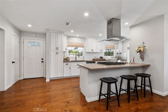 kitchen with sink, white cabinetry, island exhaust hood, a breakfast bar, and dark wood-type flooring