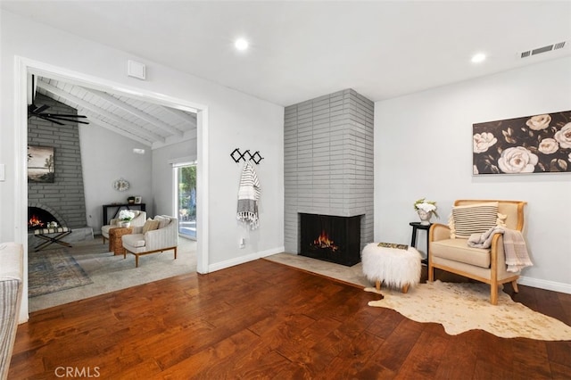 sitting room featuring wood-type flooring, a fireplace, and lofted ceiling with beams