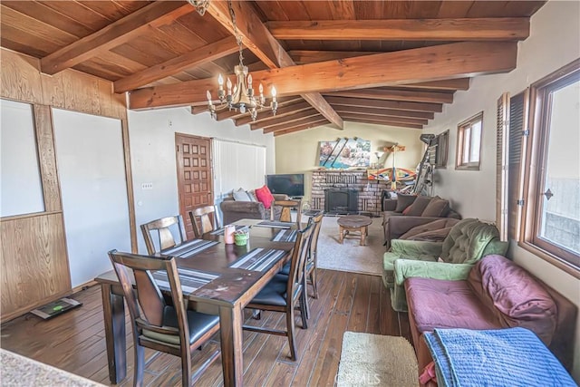 dining space with a notable chandelier, a wood stove, dark hardwood / wood-style flooring, wooden ceiling, and vaulted ceiling with beams