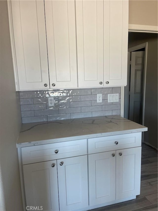 kitchen with white cabinets, tasteful backsplash, dark hardwood / wood-style floors, and light stone countertops