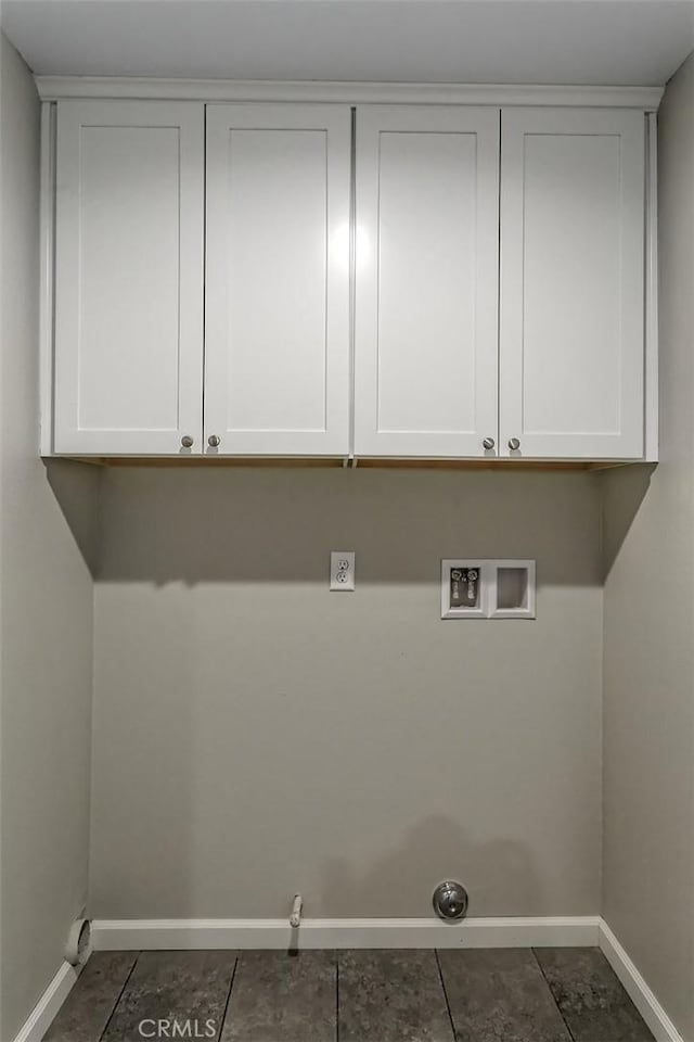 laundry area featuring gas dryer hookup, hookup for a washing machine, cabinets, and dark tile patterned flooring