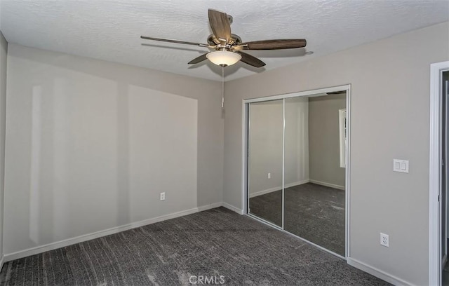 unfurnished bedroom featuring dark carpet, a closet, ceiling fan, and a textured ceiling