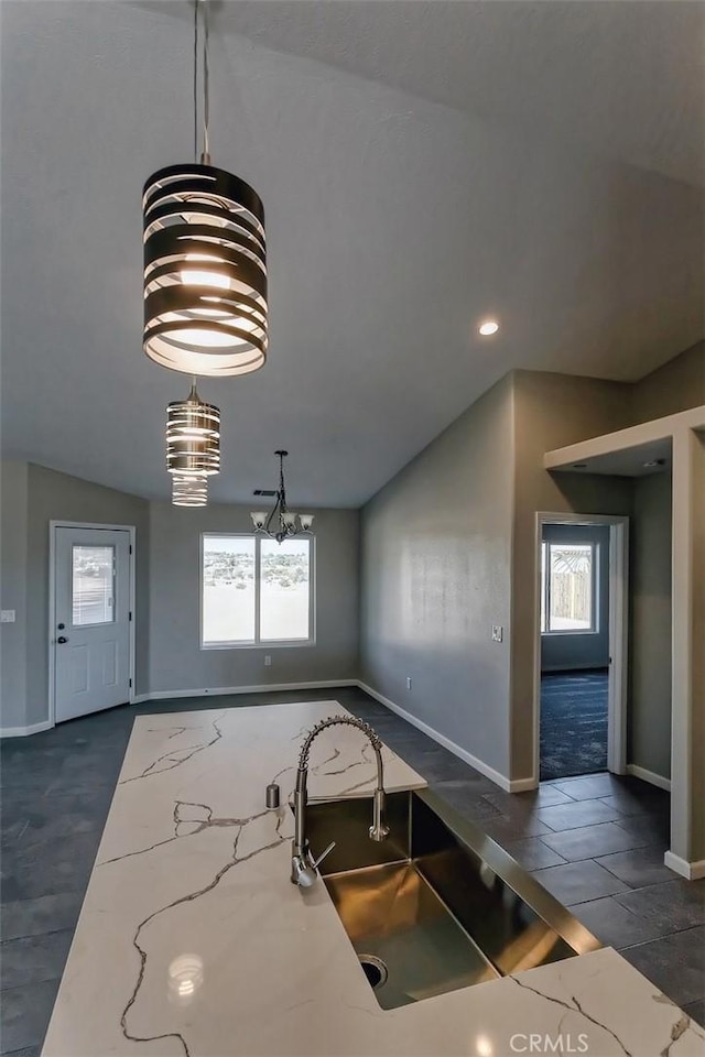 kitchen with lofted ceiling, decorative light fixtures, a healthy amount of sunlight, and light stone counters