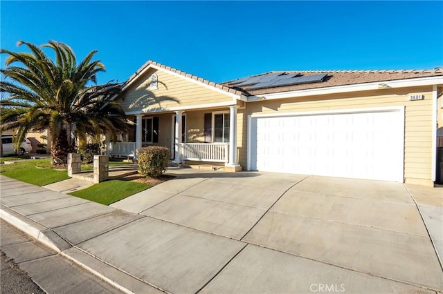 single story home with a porch, solar panels, and a garage