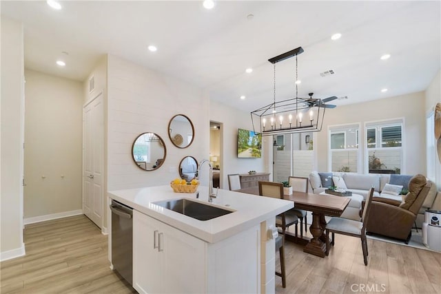 kitchen with sink, dishwasher, white cabinetry, a center island with sink, and decorative light fixtures