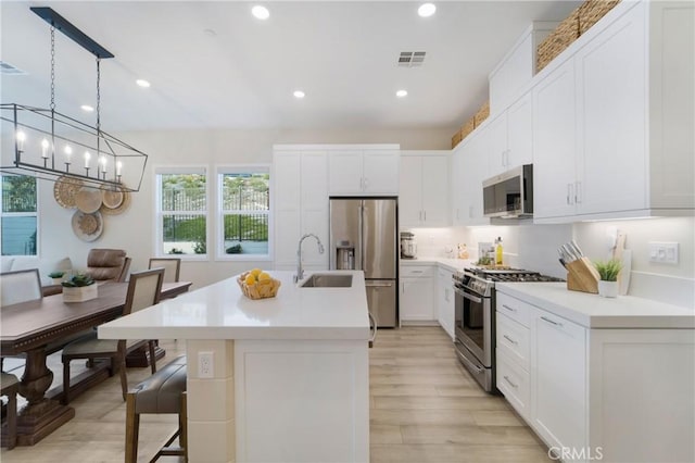 kitchen featuring white cabinetry, sink, a kitchen breakfast bar, stainless steel appliances, and a center island with sink