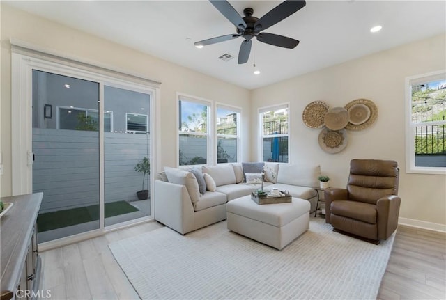 living room featuring ceiling fan, plenty of natural light, and light wood-type flooring