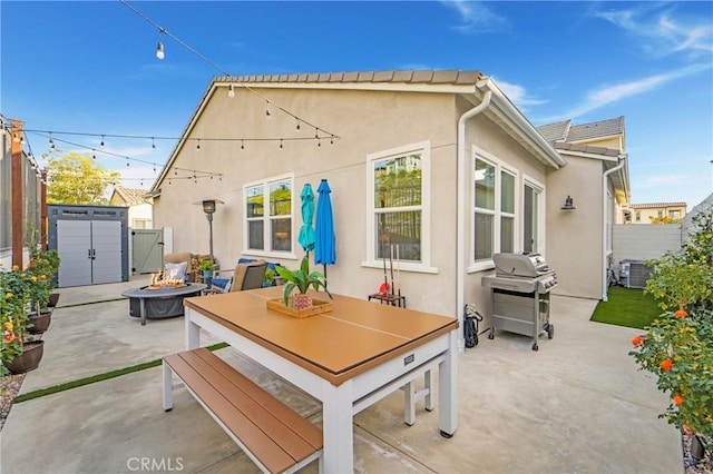 back of house with a patio, a storage unit, and an outdoor fire pit