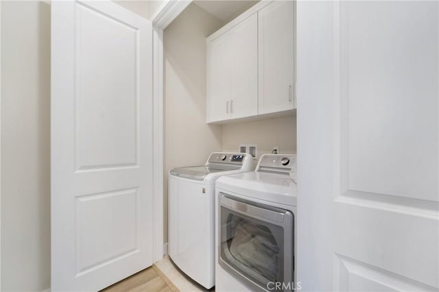 washroom with light hardwood / wood-style floors, washing machine and dryer, and cabinets