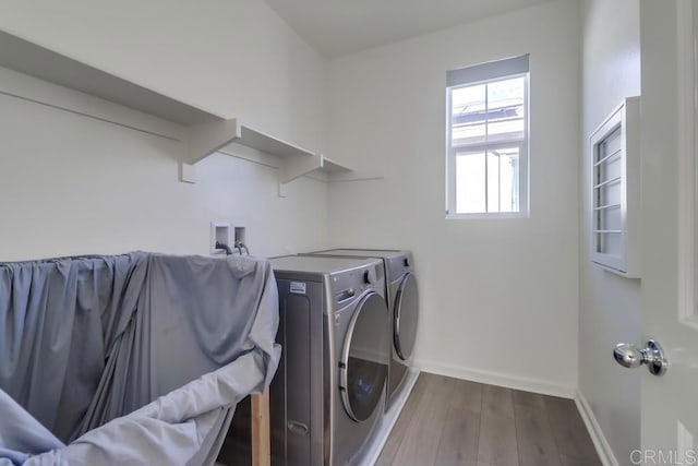 clothes washing area with washing machine and dryer and hardwood / wood-style flooring