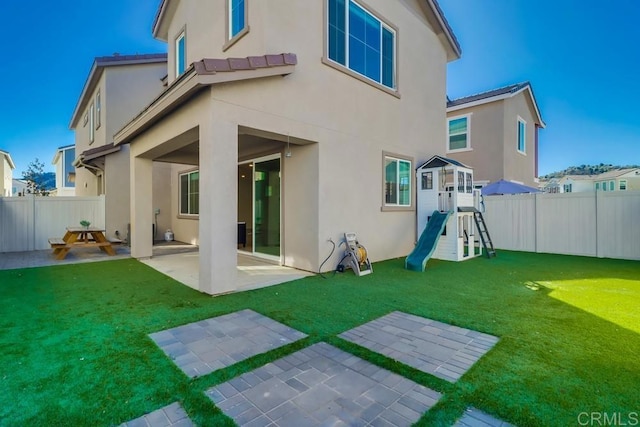 rear view of property featuring a patio, a playground, and a lawn