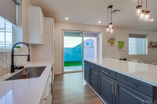 kitchen with pendant lighting, sink, white cabinetry, blue cabinets, and backsplash