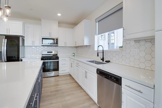 kitchen with tasteful backsplash, appliances with stainless steel finishes, pendant lighting, white cabinets, and sink