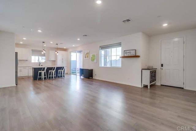 unfurnished living room with sink and light hardwood / wood-style flooring