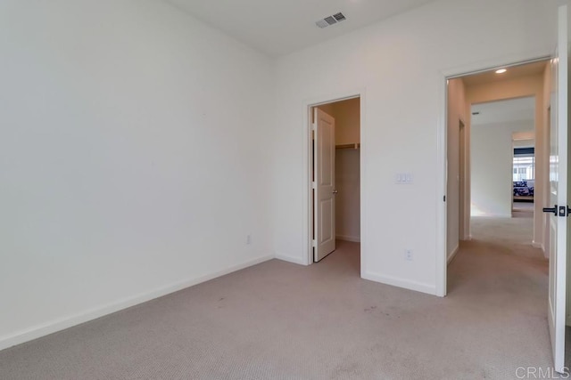 unfurnished bedroom featuring light colored carpet, a closet, and a spacious closet