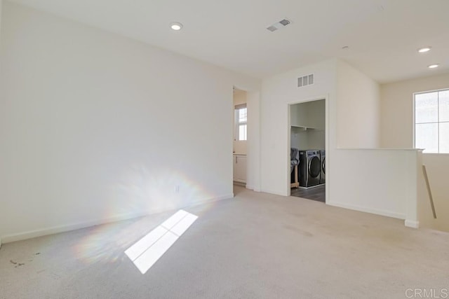 empty room featuring washer and dryer, a healthy amount of sunlight, and light carpet