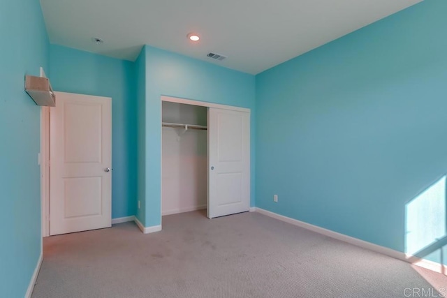 unfurnished bedroom with light colored carpet and a closet