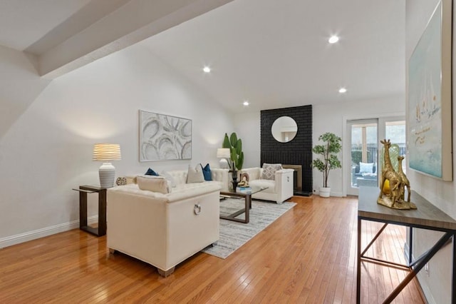 living room featuring a fireplace, vaulted ceiling, and light hardwood / wood-style flooring