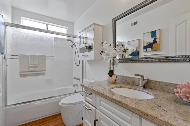 full bathroom featuring enclosed tub / shower combo, wood-type flooring, vanity, and toilet