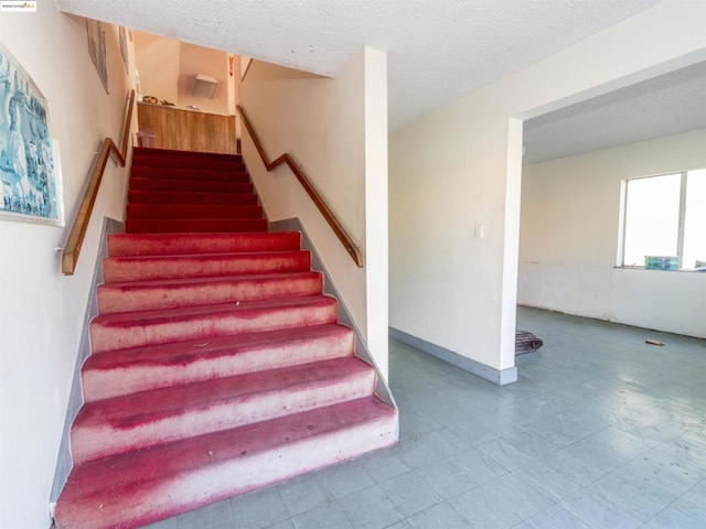 staircase featuring a textured ceiling