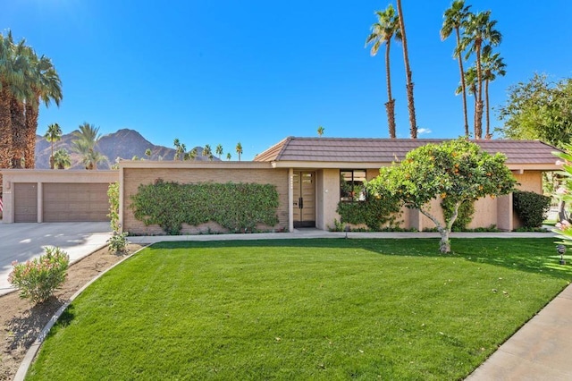 view of front facade with a front yard, a garage, and a mountain view