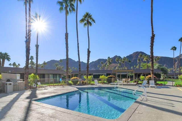 view of swimming pool featuring a mountain view, a patio area, and exterior kitchen