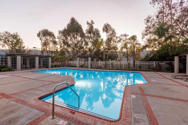 pool at dusk with a patio area