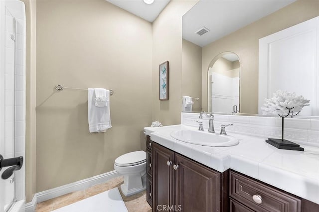 bathroom with toilet, vanity, and tile patterned floors