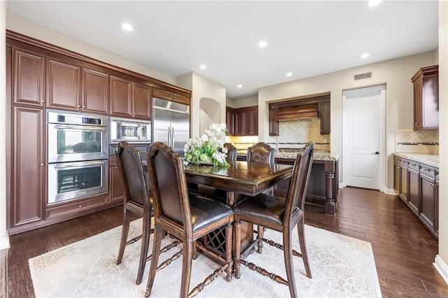 interior space with light stone counters, dark wood-type flooring, appliances with stainless steel finishes, and backsplash