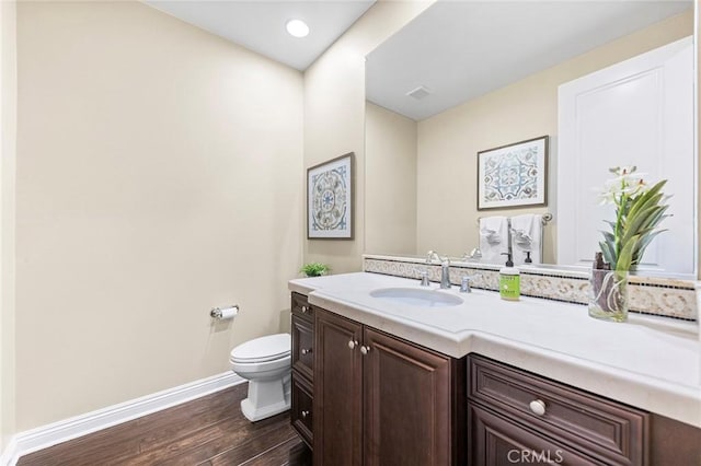 bathroom with toilet, vanity, and hardwood / wood-style flooring