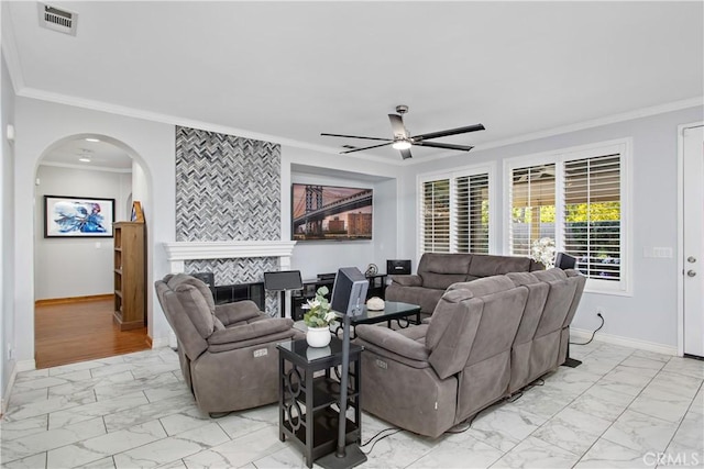 living room featuring a tiled fireplace, ceiling fan, and crown molding