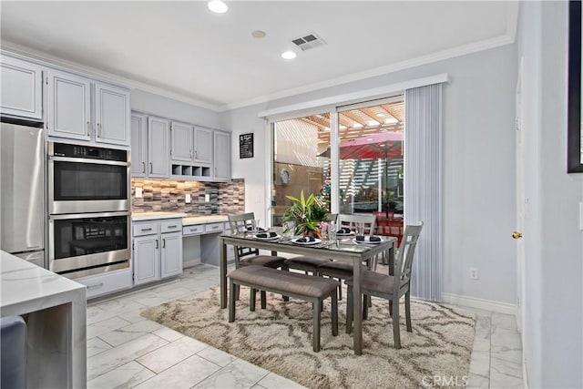 kitchen with ornamental molding, stainless steel appliances, gray cabinets, and decorative backsplash