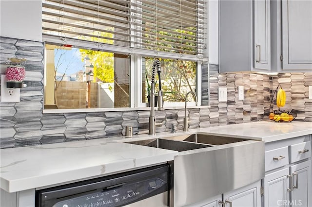 kitchen with sink, dishwasher, light stone countertops, and decorative backsplash