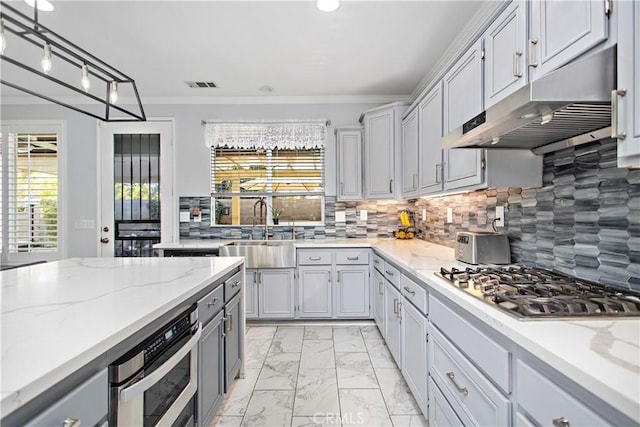 kitchen with decorative backsplash, crown molding, gray cabinetry, appliances with stainless steel finishes, and sink