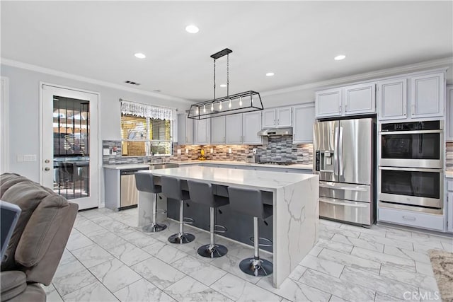 kitchen featuring stainless steel appliances, a center island, decorative light fixtures, and crown molding