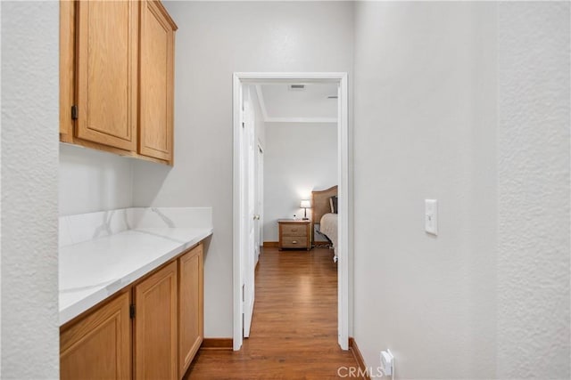 interior space with hardwood / wood-style flooring, crown molding, and light stone countertops