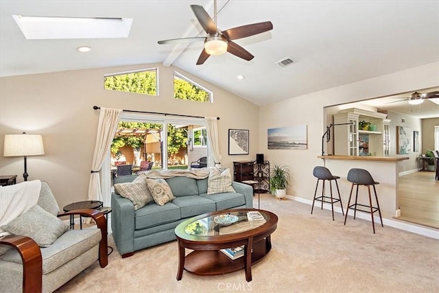 living room featuring light colored carpet, ceiling fan, and vaulted ceiling with skylight