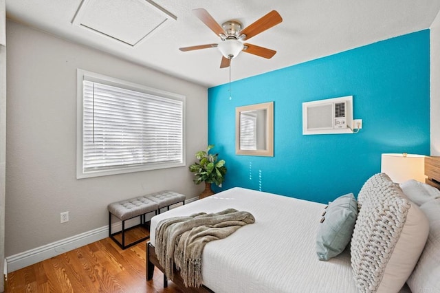 bedroom featuring ceiling fan, hardwood / wood-style floors, and a wall unit AC