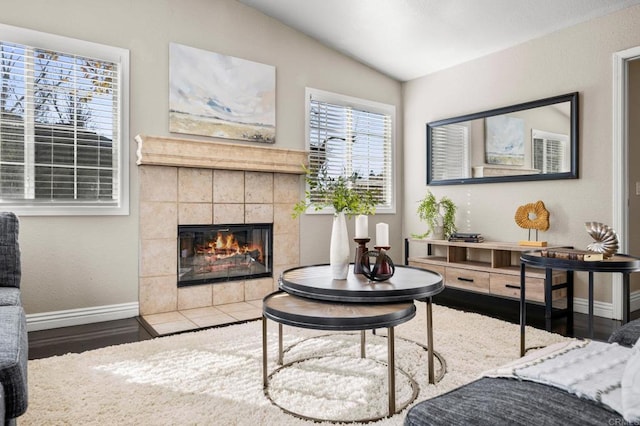 sitting room with lofted ceiling, a tile fireplace, and wood-type flooring