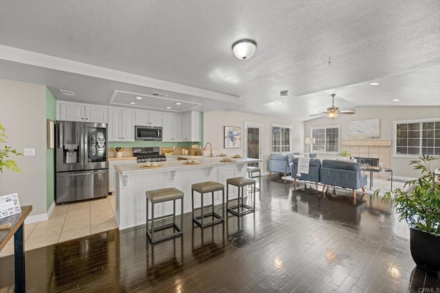 kitchen with white cabinets, ceiling fan, light hardwood / wood-style floors, a breakfast bar area, and appliances with stainless steel finishes