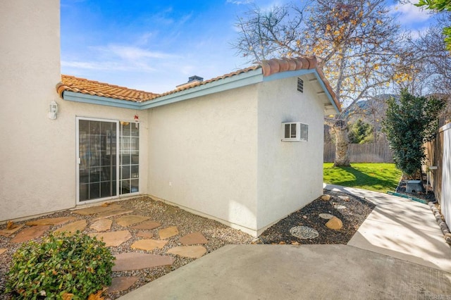 view of property exterior with an AC wall unit and a patio